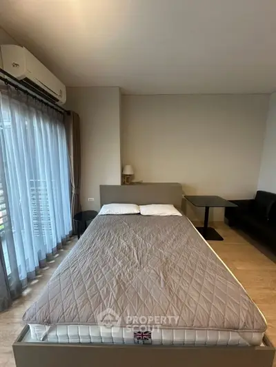 Modern bedroom with large window and stylish furnishings in a cozy apartment.