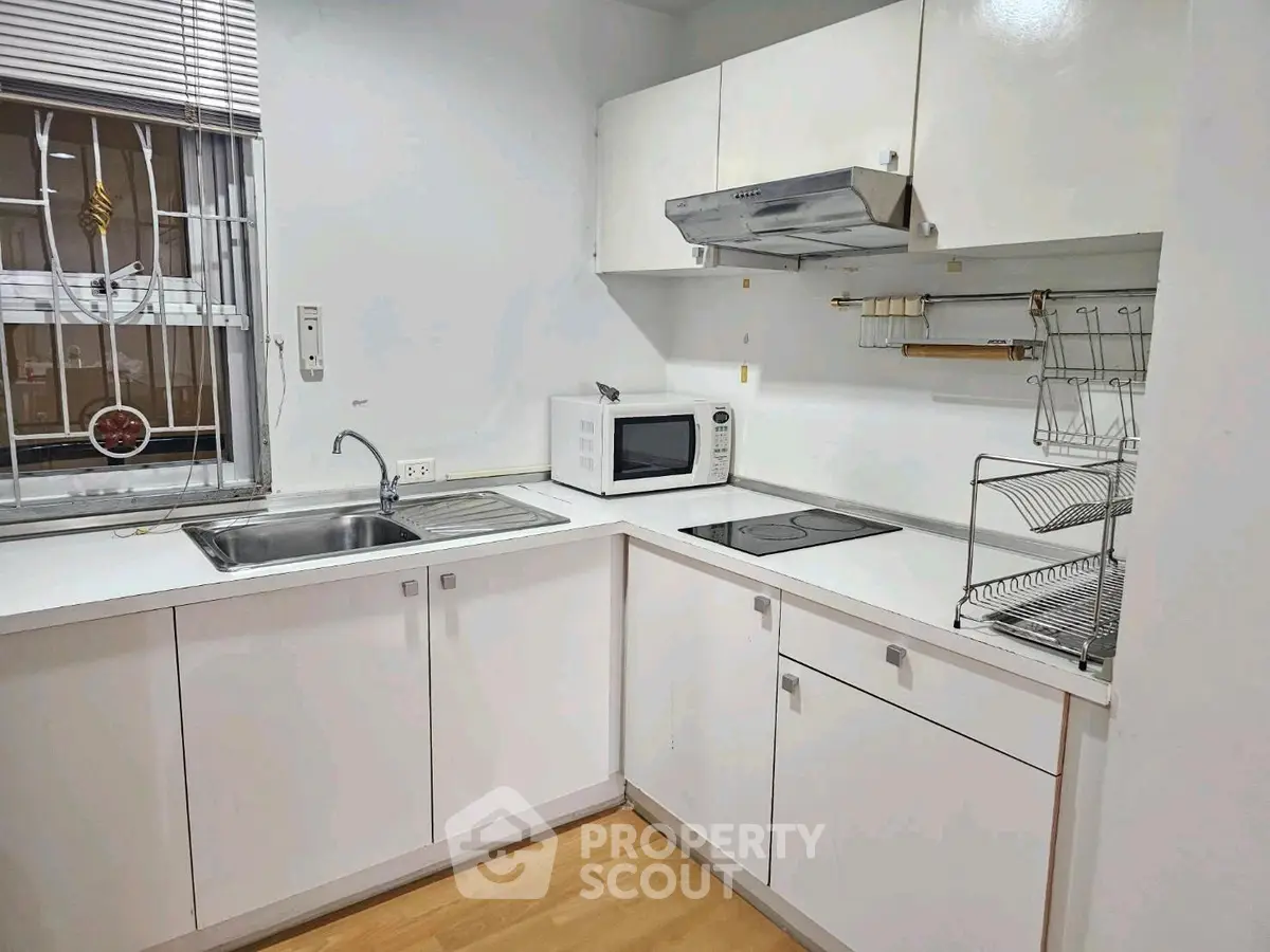 Modern kitchen with sleek white cabinets and built-in appliances, perfect for culinary enthusiasts.