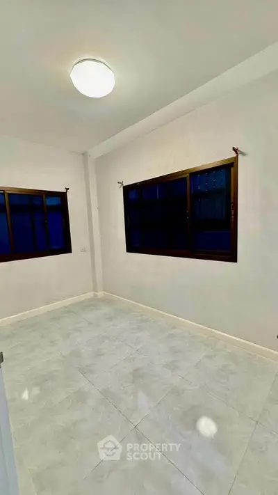 Spacious empty room with large windows and tiled flooring, perfect for customization.