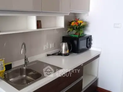 Modern kitchen with sleek cabinetry, stainless steel sink, and microwave, perfect for urban living.
