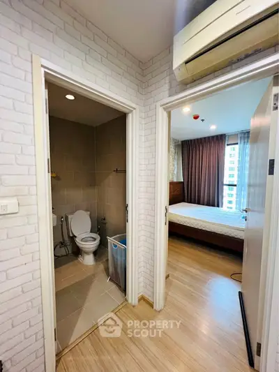 Modern apartment interior with bedroom and bathroom, featuring wood flooring and air conditioning.