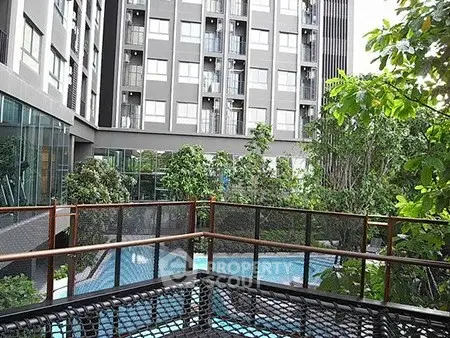 Modern apartment building with lush garden and inviting pool area.