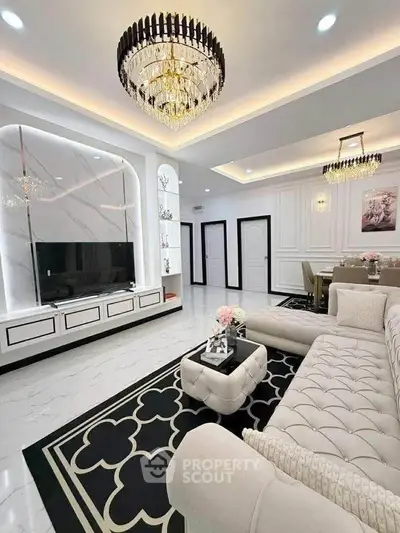 Luxurious living room with elegant chandelier and modern decor, featuring a stylish TV unit and plush seating.