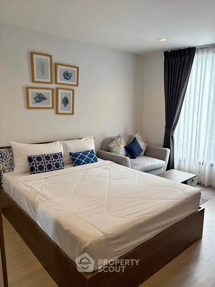 Modern bedroom with cozy decor and natural light, featuring a comfortable bed and stylish sofa.
