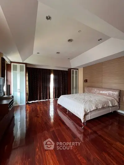 Spacious bedroom with polished wooden floors and elegant ceiling design
