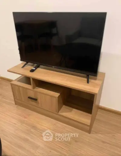 Modern living room with sleek TV stand and flat-screen television on wooden flooring.