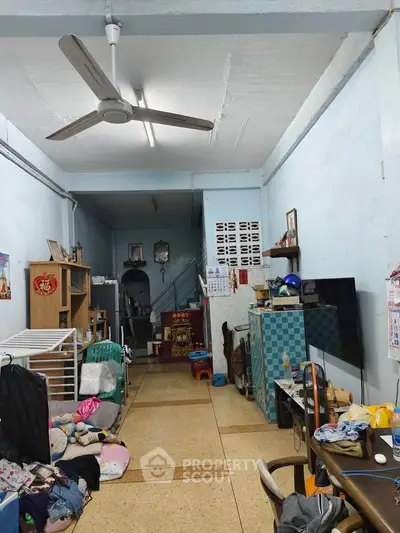 Spacious living room with ceiling fan and tiled flooring, featuring a cozy seating area and ample storage space.