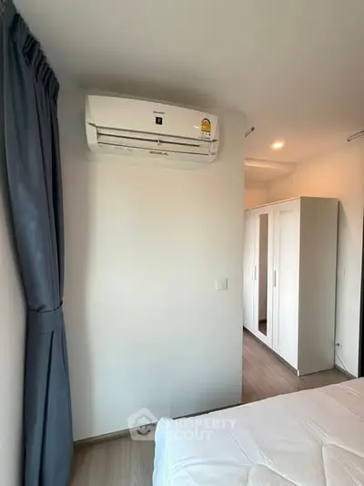 Modern bedroom with air conditioning and wardrobe, featuring sleek design and natural light.