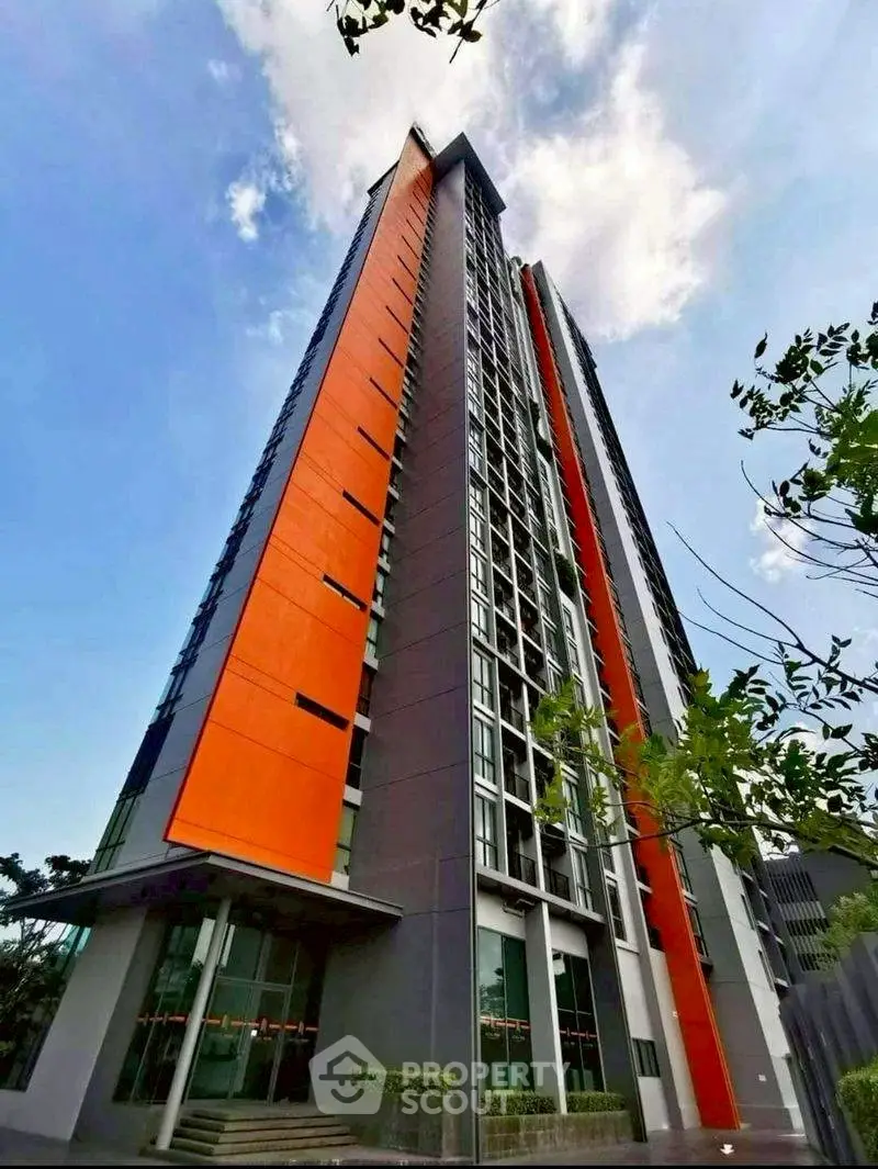 Stunning modern high-rise building with vibrant orange accents and expansive glass windows.