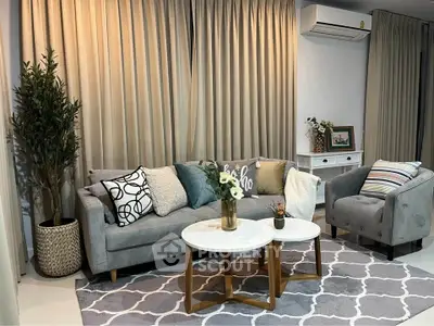Stylish living room with modern decor, featuring a cozy gray sofa, chic armchair, and elegant coffee table.