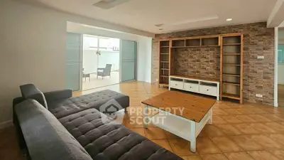 Spacious living room with modern furniture and access to a bright balcony, perfect for relaxation.