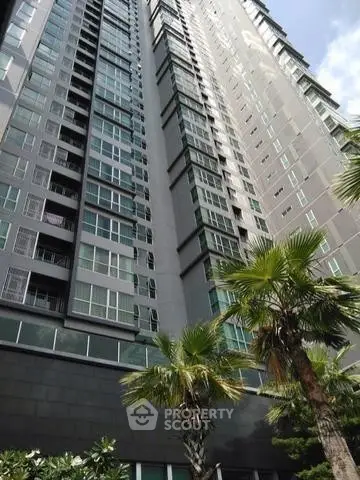 Modern high-rise building with lush palm trees and sleek glass windows.