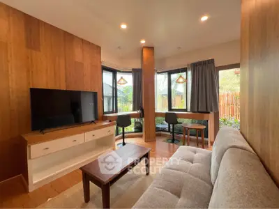 Charming living room with modern decor and large windows offering garden views.