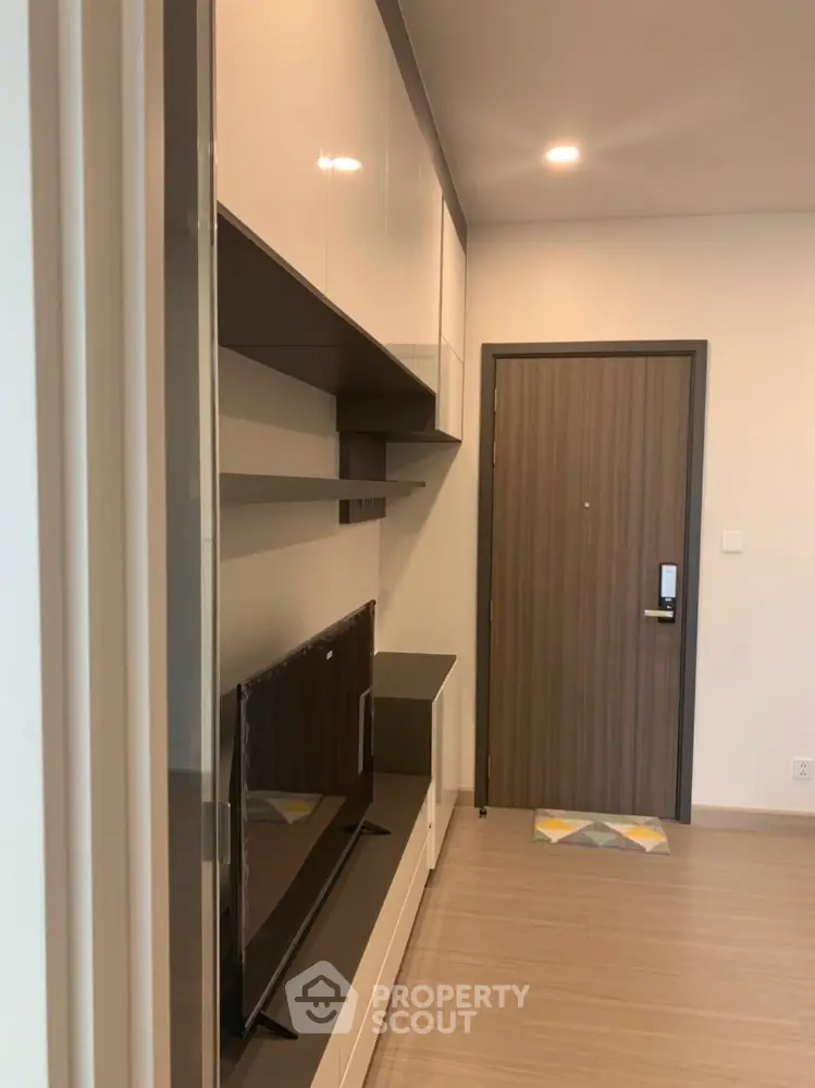 Modern apartment entrance with sleek storage and TV unit