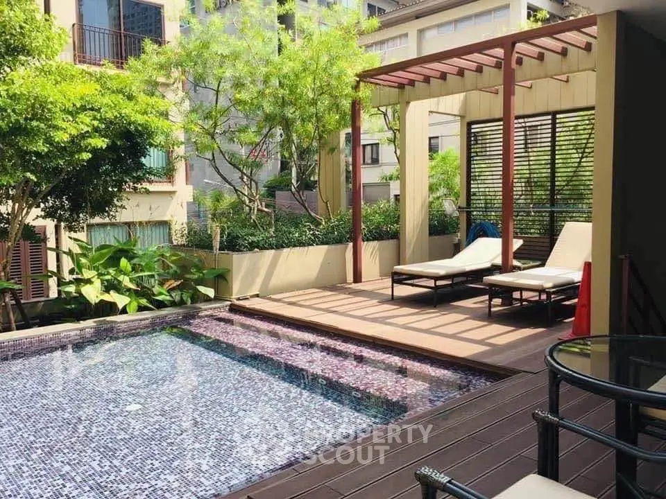 Luxurious poolside area with sun loungers and lush greenery in a modern residential complex.