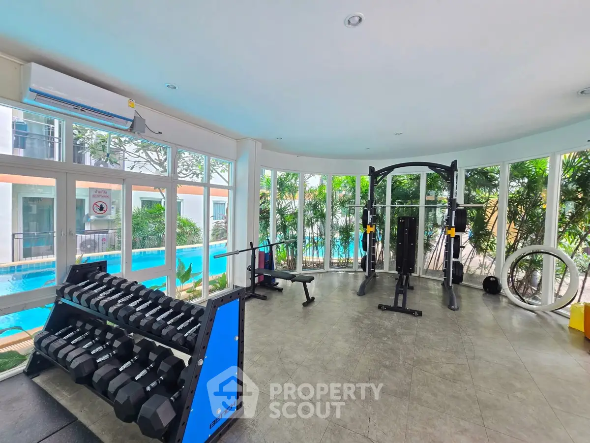 Modern gym with pool view and state-of-the-art equipment in luxury real estate property.
