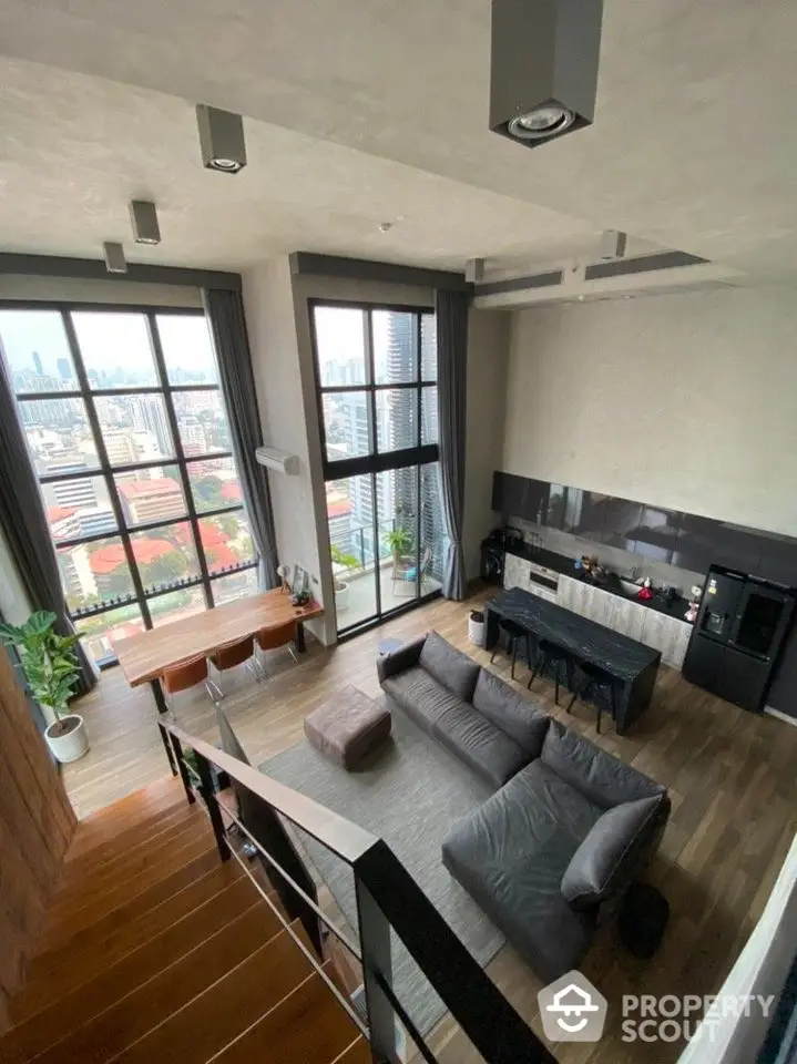 Stunning modern loft with high ceilings and panoramic city views, featuring open-plan kitchen and spacious living area.