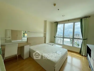 Bright bedroom with large window offering city views, featuring a comfortable bed and stylish desk.
