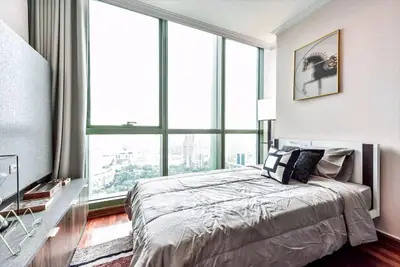 Luxurious bedroom with floor-to-ceiling windows offering stunning city views, elegant decor, and modern furnishings.