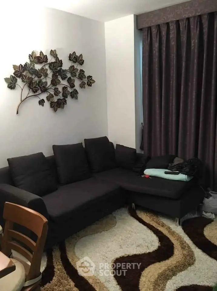 Cozy living room with dark sofa and decorative wall art, perfect for relaxation.