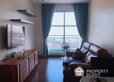 Inviting living room with plush leather sofa, large windows offering ample natural light, and a spacious balcony with a relaxing view, perfect for urban living.