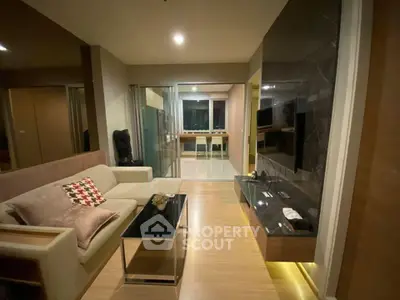 Modern living room with stylish decor and open layout leading to a sleek kitchen area.
