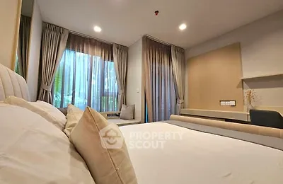 Spacious bedroom with large windows and elegant curtains in modern apartment.