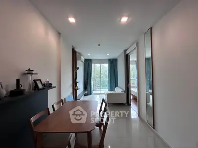 Modern living room with dining area and large windows offering natural light and greenery view.