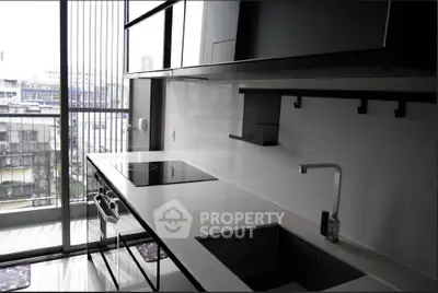 Modern kitchen with sleek design and city view, featuring induction cooktop and minimalist cabinetry.