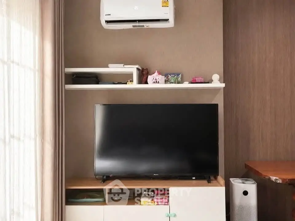 Modern living room with sleek TV setup and air conditioning unit, perfect for cozy entertainment.