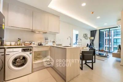 Modern open-plan kitchen and living room with washing machine and stylish decor.