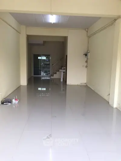 Spacious open-plan interior with glossy tiled flooring and staircase access