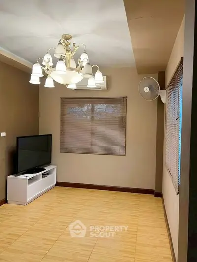 Cozy living room with elegant chandelier and modern TV setup, perfect for relaxation and entertainment.