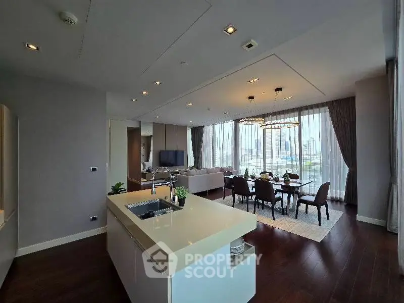 Luxurious open-plan living and dining area with city view, featuring modern kitchen island and elegant decor.