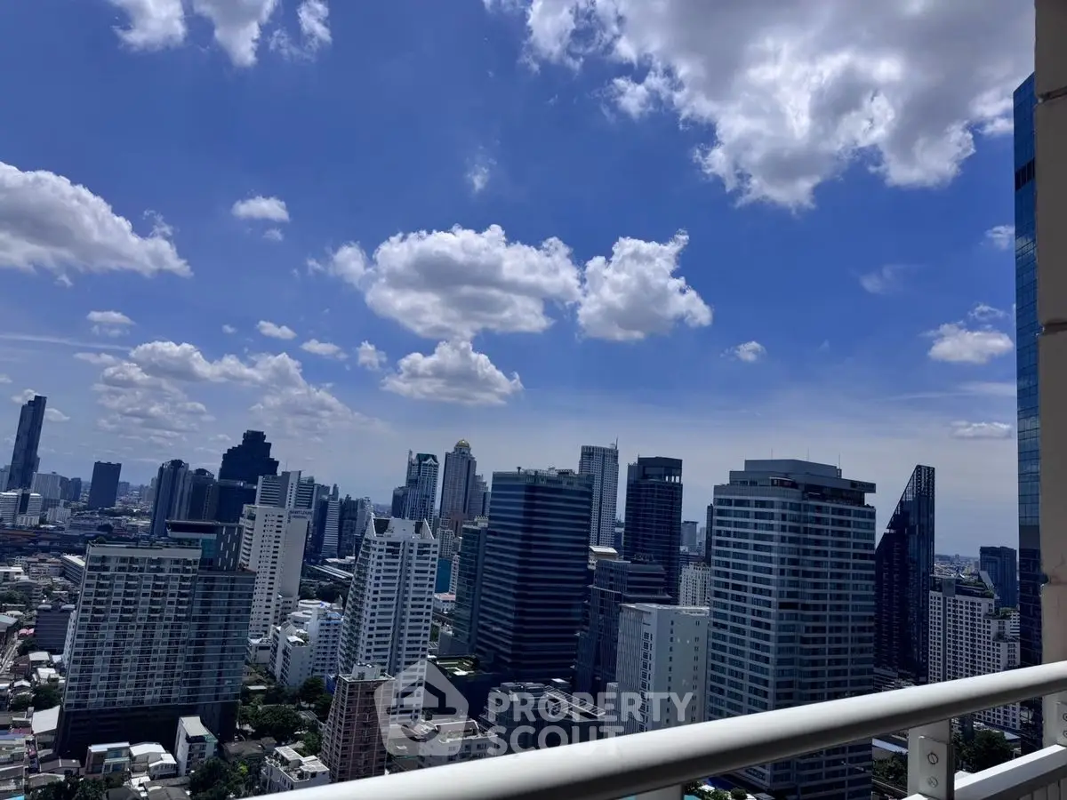 Stunning city skyline view from high-rise balcony with blue sky and clouds.