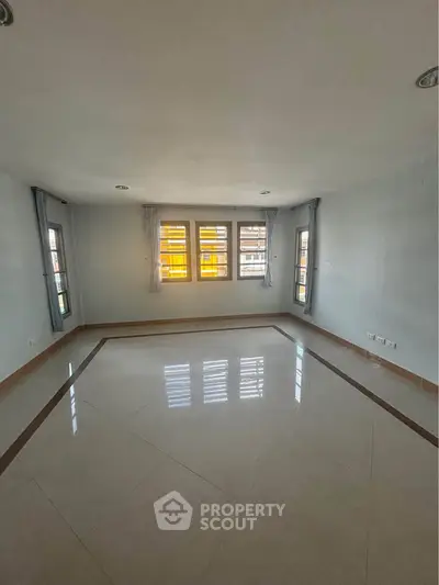 Spacious empty room with large windows and tiled flooring, perfect for customization.