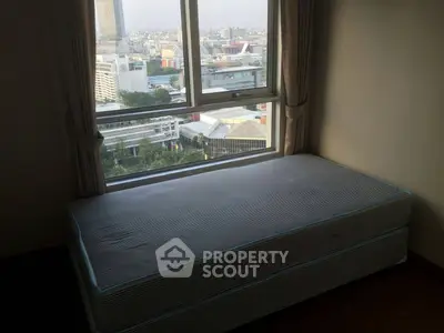 City view from a high-rise apartment with a single bed by the window, offering urban living experience.