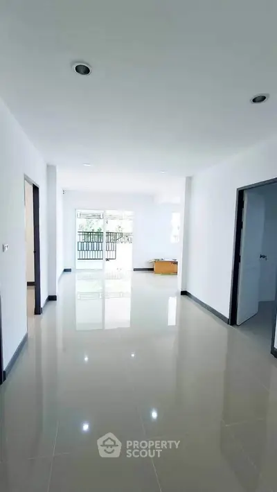 Spacious and bright living area with glossy tiled floors and balcony access.