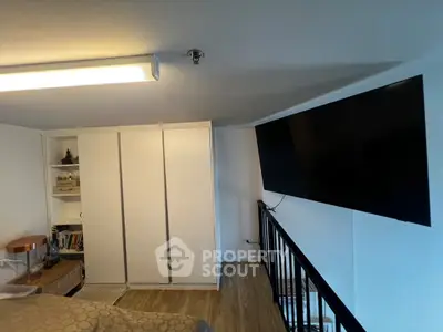 Modern bedroom with sleek design, featuring a large TV and stylish storage solutions.