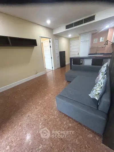 Spacious living room with modern sofa and open kitchen layout, ideal for cozy gatherings.