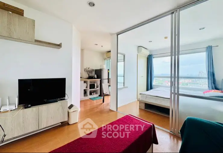 Modern apartment with open living room and bedroom, featuring large windows and city view.
