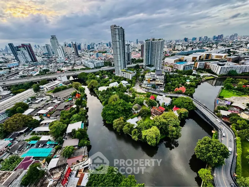 Stunning aerial view of urban skyline with river and lush greenery, showcasing modern high-rise buildings and vibrant cityscape.