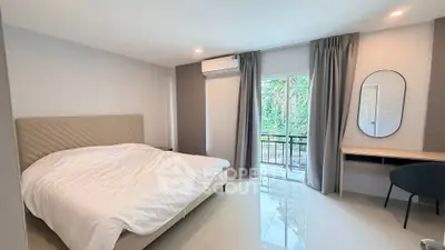 Spacious bedroom with modern decor and large window overlooking greenery, featuring a cozy bed and stylish furniture.