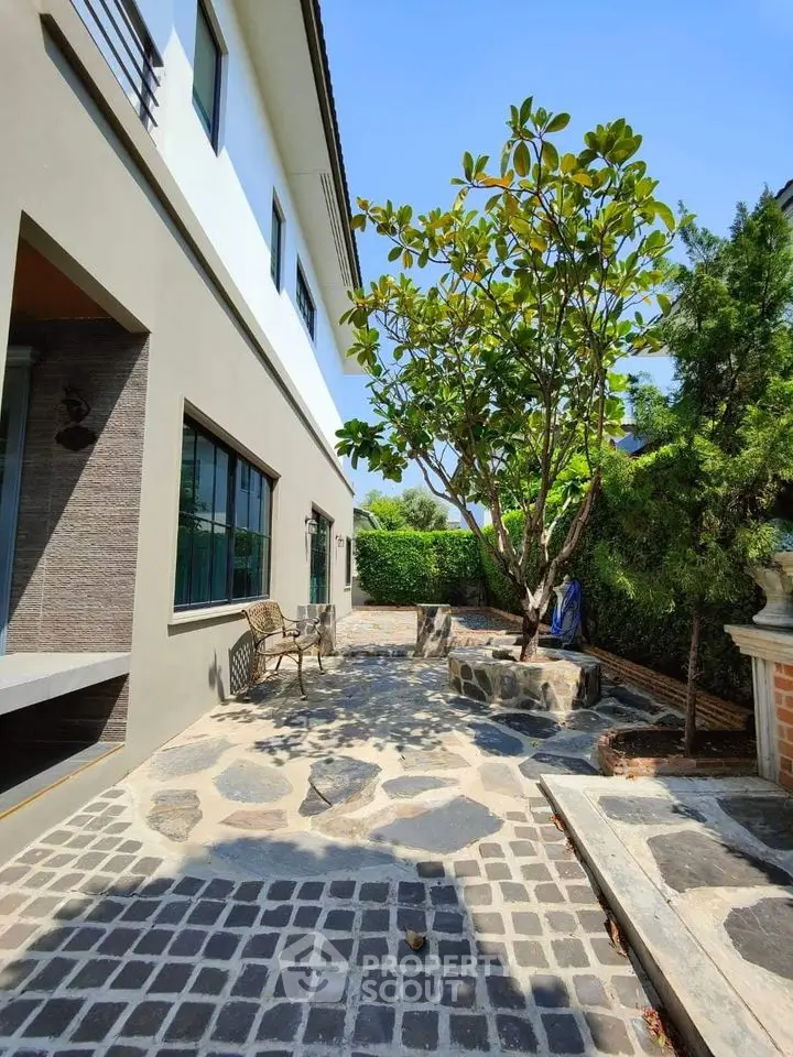 Charming modern home exterior with spacious stone patio and lush greenery