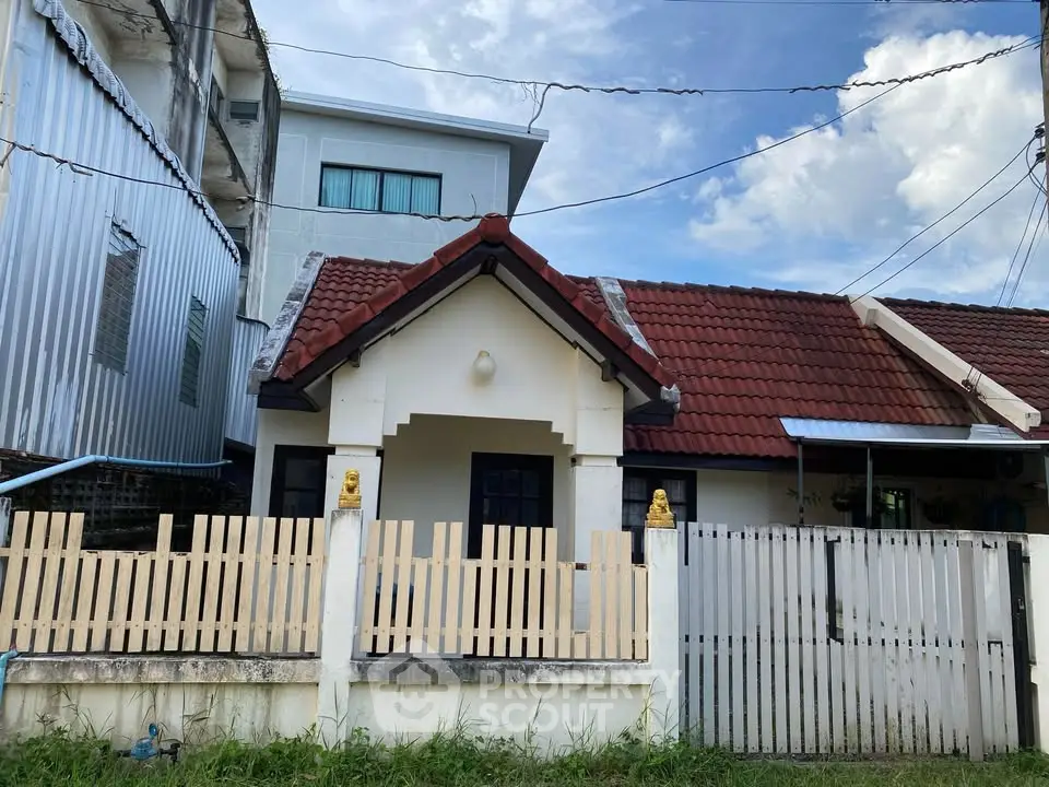 Charming single-story house with red-tiled roof and fenced yard, perfect for cozy living.