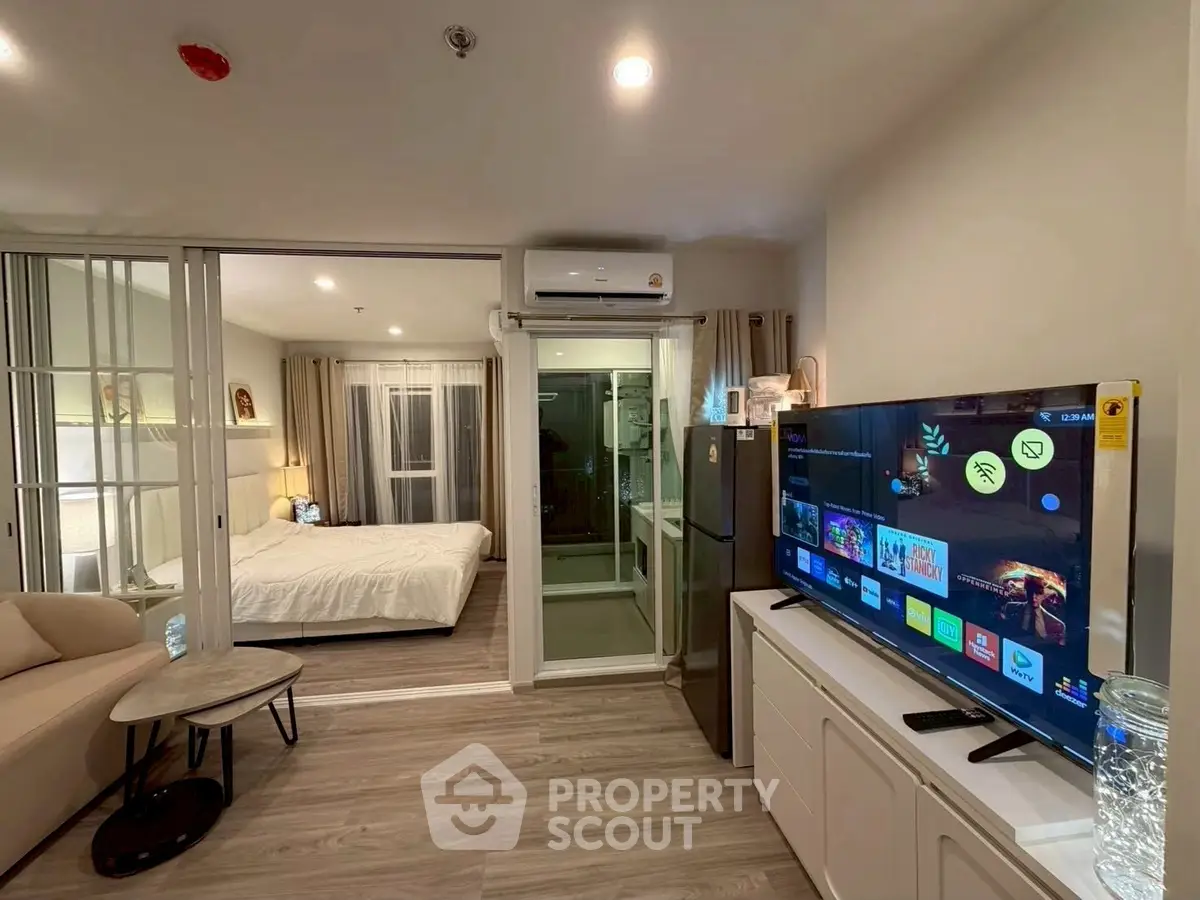 Modern living room with TV and view into cozy bedroom