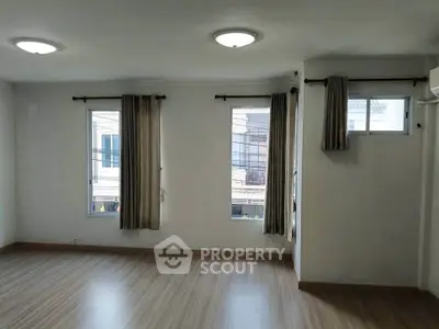 Spacious empty room with large windows and wooden flooring, perfect for customization.