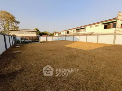 Spacious fenced backyard with dry grass and clear blue sky, ideal for landscaping or outdoor activities.