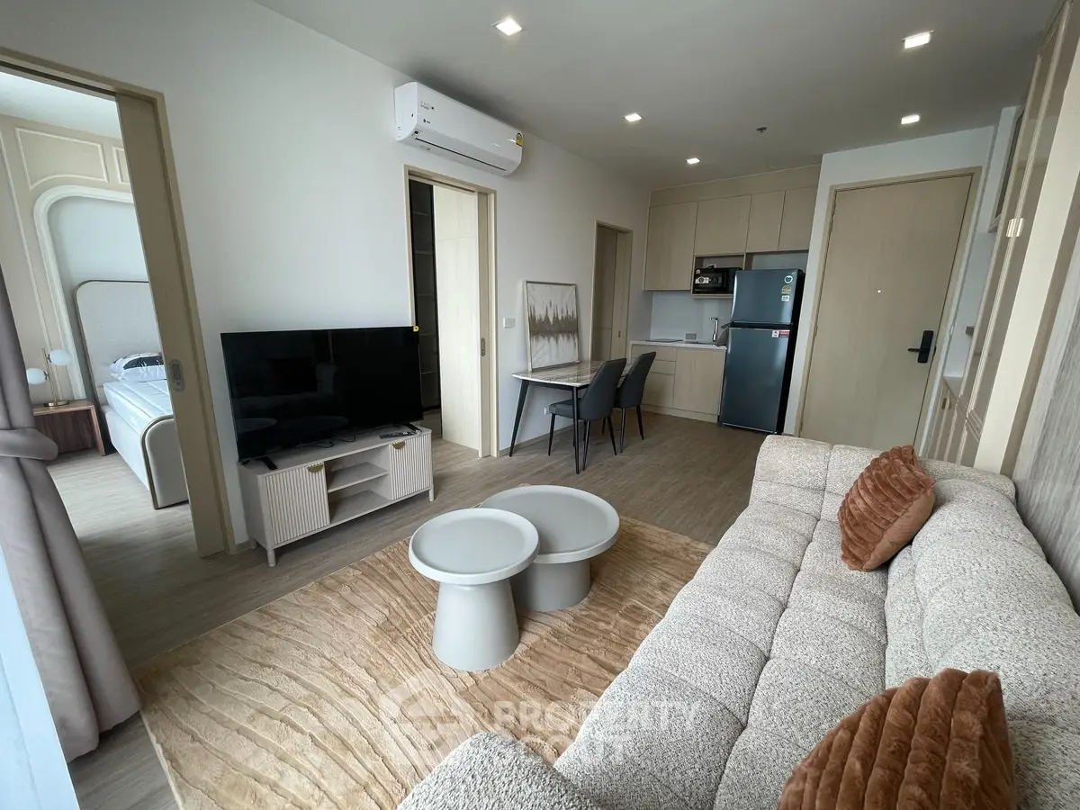 Modern living room with cozy sofa, TV, and compact kitchen area in open layout apartment.