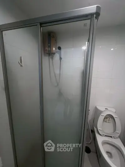 Compact bathroom with shower enclosure and modern toilet in a sleek design.